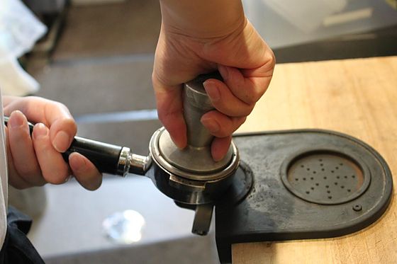 Pressing the ground coffee into the portafilter with a tamper