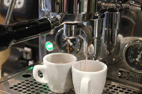 Espresso pouring from the portafilter spouts into 2 cups
